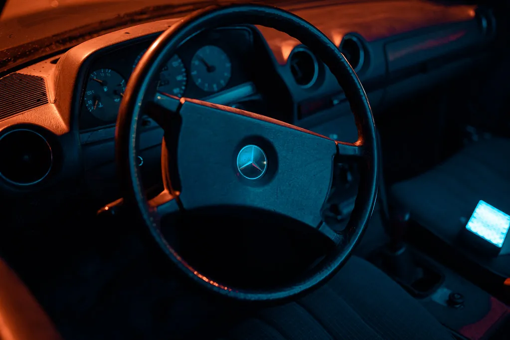 Vista del conductor de un volante y tablero de un auto clásico de noche