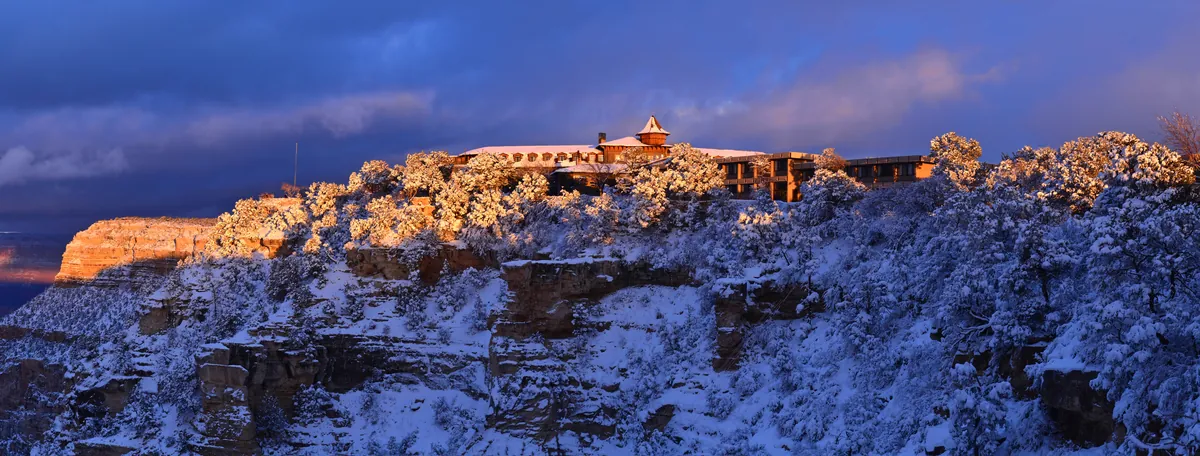 A remote mountain lodge illuminated at dusk after snowfall
