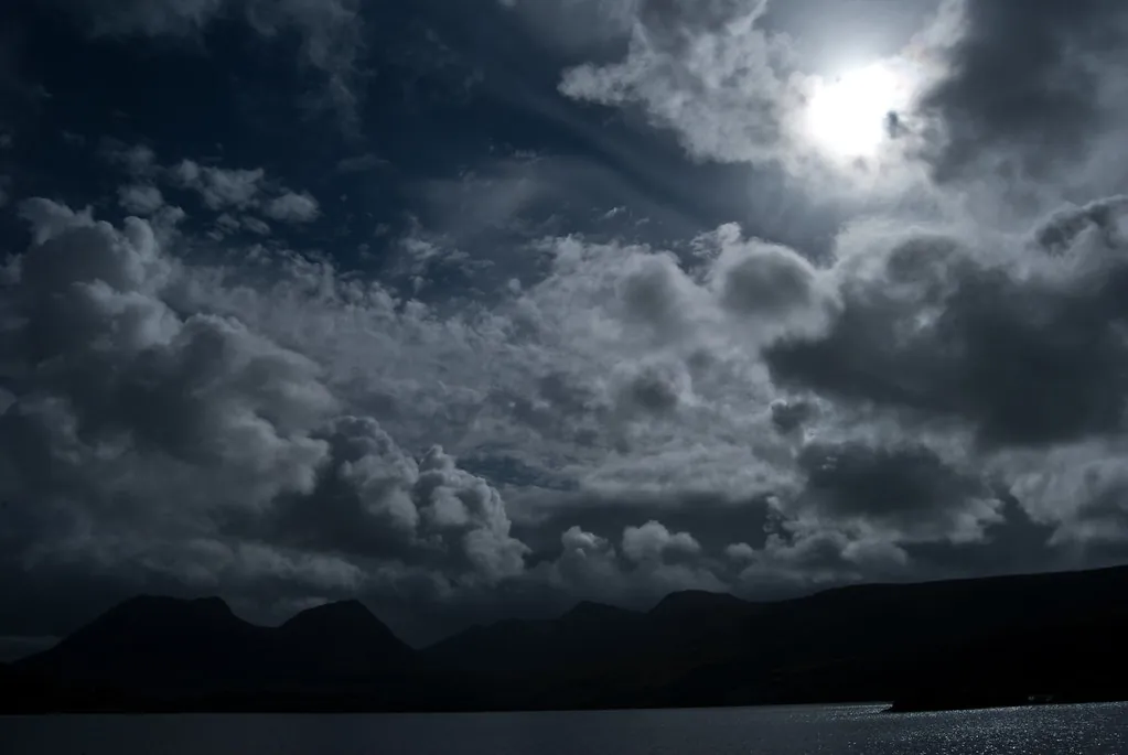 Un cielo iluminado por la luna sobre montañas oscuras, a la espera de la revelación